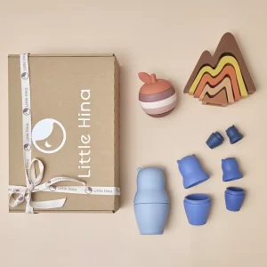 Set Nos Vamos de Aventura con juguetes educativos: montaña apilable Alba, manzana encastrable Mariana y Osusko, inspirado en la matrioska rusa, ideales para fomentar creatividad y habilidades motoras.